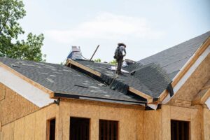 Homeowner reviews an insurance policy beside roof damage photos and a folder of maintenance records.