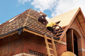 A homeowner observes missing shingles and a ceiling stain beneath a leaking residential roof.